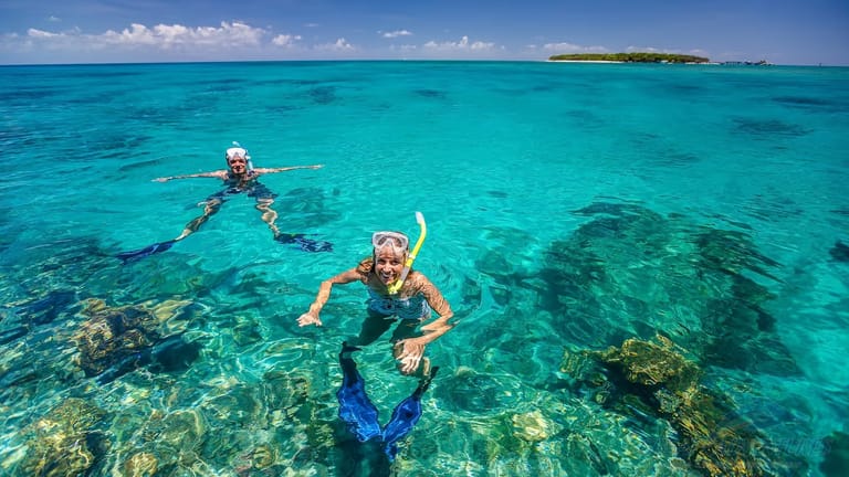 Two snorkellers posing for camera with Green Island in the background.