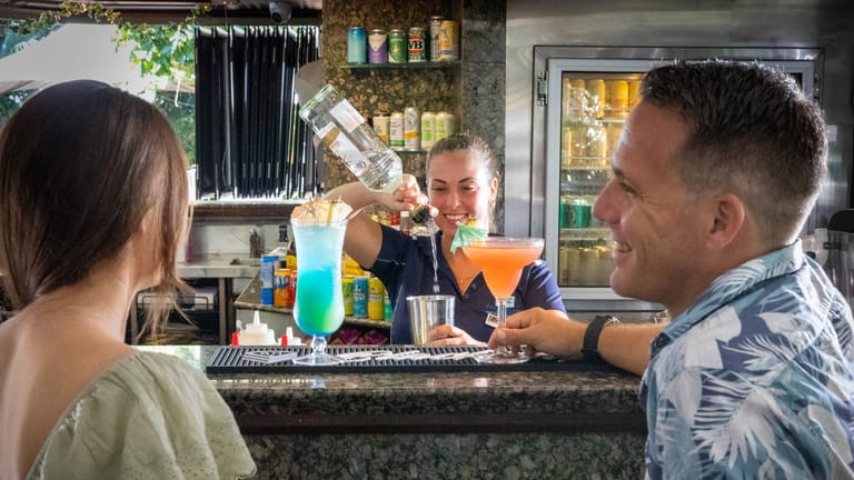 Bartended serving various colourful cocktails at a pool bar.