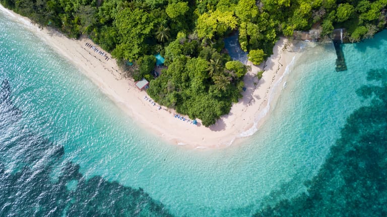 Directly overhead shot of the edge of Green island, its beach and blue water.