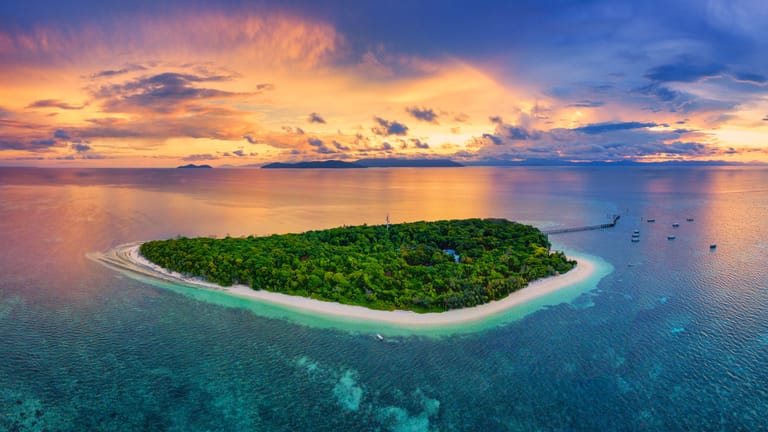 Aerial view of Green Island with a strong orange sunset behind it.