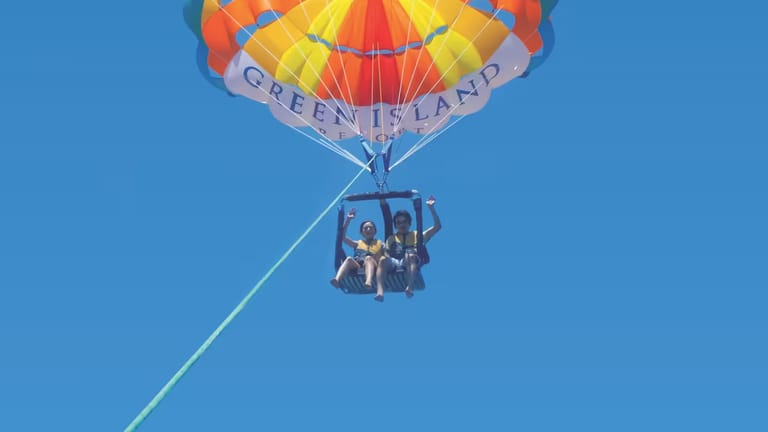 Two people in a parasailing seat, viewed from below.