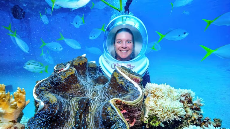 A Seawalker diver posing behind a giant clam